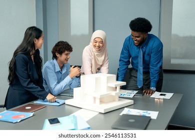 Diverse team of professionals gathered around a table, discussing an architectural model and plans during a creative office meeting. - Powered by Shutterstock