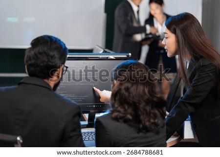 A diverse team of software developers examining computer code on a monitor, focusing on debugging or code review. Mentorship, technical training. Developing application program, Cybersecurity center