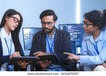 Diverse team of software engineers and data scientists collaborating on a project, using tablets and analyzing code. Concept for AI development, cybersecurity, and tech innovation.