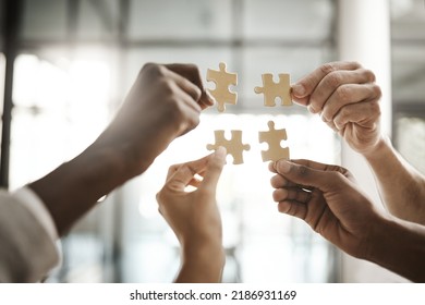 Diverse team solving a problem together due to teamwork, support and helping each other in the office. Group of business people assembling a puzzle and collaborating in unity - Shutterstock ID 2186931169