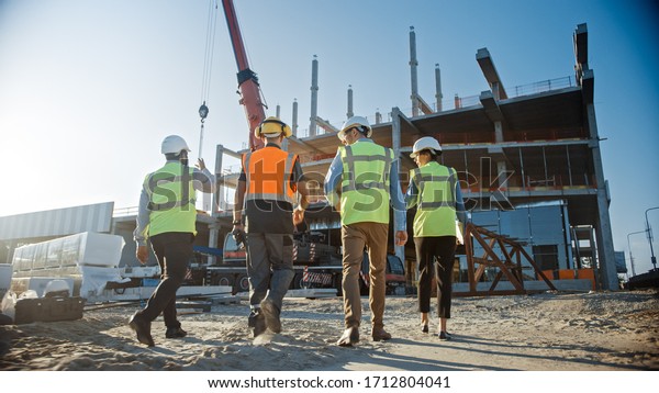 Diverse Team of Specialists Inspect Commercial,\
Industrial Building Construction Site. Real Estate Project with\
Civil Engineer, Investor and Worker. In the Background Crane,\
Skyscraper Formwork\
Frames
