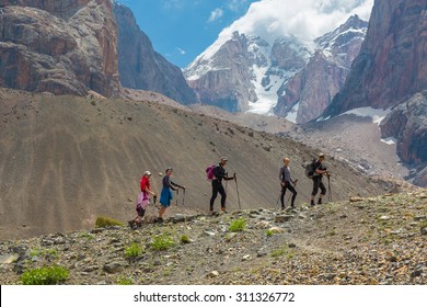 Diverse Team Walking On Rocky Ridge.
Grassy Ridge And Group Of People Walking With Hiking Gear Severe High Mountain Landscape Background Blue Sky White Clouds