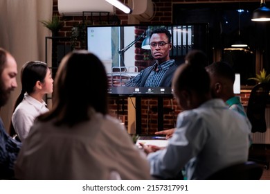 Diverse Team Working Overtime Discussing With Remote Manager During Online Video Call Conference Late At Night In Company Office Room. Focused Colleagues In Internet Meeting With Business Owner.