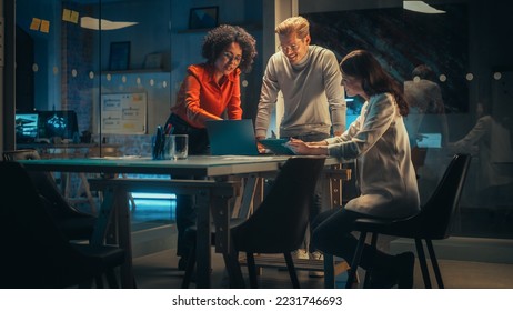 Diverse Team of Young Managers Discussing Work at a Meeting in Office at Night. Successful Business Partners Talking About a Marketing Campaign, Getting Familiar with Company Reports - Powered by Shutterstock