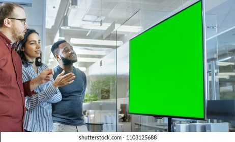 Diverse Team Of Young People In Conference Room Have Discussion About Green Screen Chroma Key Template Shown On A Presentation TV.