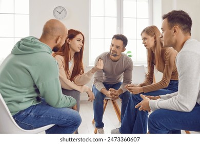 Diverse team of young people sits in a circle, engaged in a lively discussion. They are talking, communicating, and working together in group, showcasing the essence of teamwork and collaboration. - Powered by Shutterstock