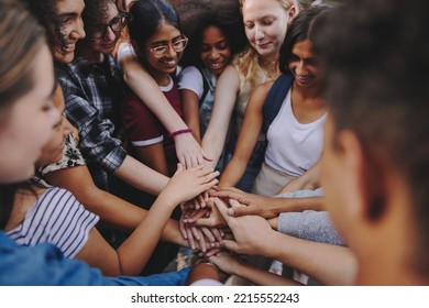 Diverse Teenagers Smiling Happily While Putting Their Hands Together In A Huddle. Group Of Multicultural Young Kids Symbolizing Unity And Teamwork.