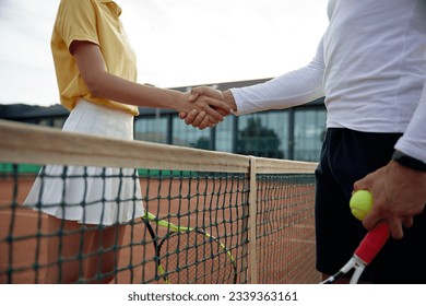 Diverse tennis players shaking hands after successful training on court - Powered by Shutterstock