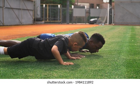 Diverse trainer and boy doing push ups on field - Powered by Shutterstock