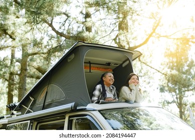 Diverse Traveling Women Relaxing In Tent On Roof Of Car