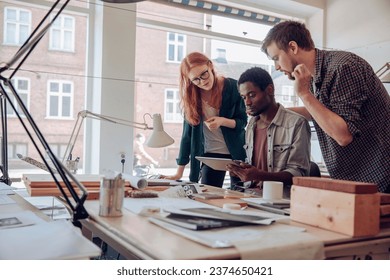 Diverse trip of young architects using a tablet together in a office - Shutterstock ID 2374650421
