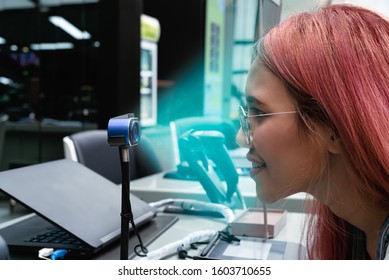 Diverse woman using biometric scanner to confirm identity and pay for retail shopping transaction - Young girl using facial recognition ID at bank - Cyber security, verification and cashless concept - Powered by Shutterstock