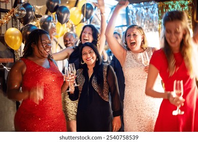 Diverse women celebrating at a party with balloons and drinks, smiling and cheering. Festive atmosphere with friends enjoying a joyful celebration. Friends celebrating New Year's eve with champagne. - Powered by Shutterstock