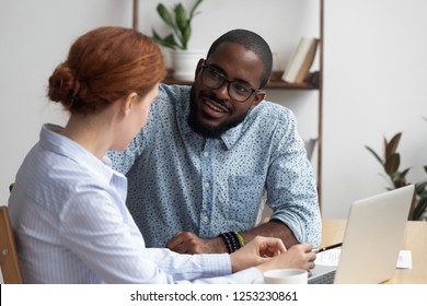 Diverse workmates take break during workday talking have pleasant conversation feels amity interest to each other. Multiracial businesspeople negotiating in relaxed atmosphere solve business issues