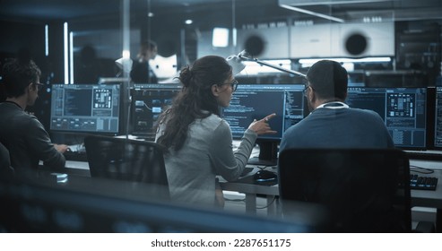 Diverse Young Colleagues Working on Computers in a Research Laboratory. Female Asking Advice from a Male Software Developer Colleague About a Solution for Their Collaborative Industrial Tech Project - Powered by Shutterstock