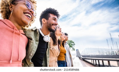 Diverse young friends hugging each other outdoors - Multiethnic group of people  standing together showing unity and teamwork - Support and community concept