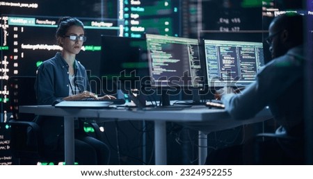 Diverse Young Man and Woman Working on Desktop Computers, Surrounded by Big Screens Displaying Code Prompts. Professional Computer Engineers Developing Autonomous Algorithm for Generative AI.