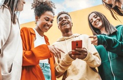 Diverse Young People Using Smart Mobile Phone Device Outdoors - Multiracial Friends Watching Smartphone Together - Teenagers Uploading Reel Video On Social Media Platform - Youth Culture Concept