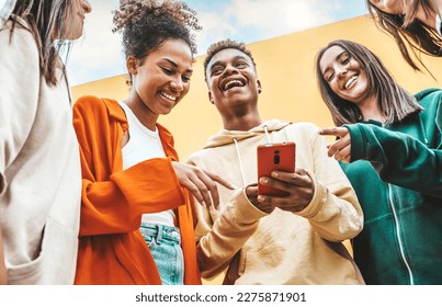 Diverse young people using smart mobile phone device outdoors - Multiracial friends watching smartphone together - Teenagers uploading reel video on social media platform - Youth culture concept - Shutterstock ID 2275871901