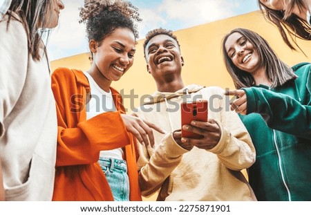 Diverse young people using smart mobile phone device outdoors - Multiracial friends watching smartphone together - Teenagers uploading reel video on social media platform - Youth culture concept 商業照片 © 