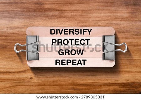 Diversify Protect Grow Repeat tagline written on wooden stick hold by binder clip with wooden texture background, business and investment, stock market theme