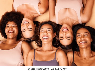 Стоковая фотография: Diversity, beauty and portrait of women from above with smile, self love and solidarity in studio. Happy face, group of friends on beige background with underwear, skincare and cosmetics on floor.