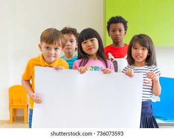 Diversity Children Holding Blank Poster In Classroom At Kindergarten Preschool,Multi Ethnic Group With Sign Board,mock Up For Adding Text Or Design.