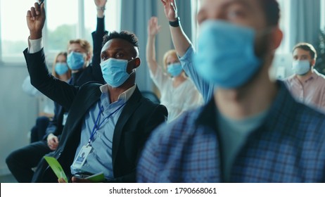 Diversity Of Corporate People In Masks Participating In Conference Meeting Business Seminar, Raising Hands To Ask The Speaker. Presentation. Social Distance. Coronavirus.