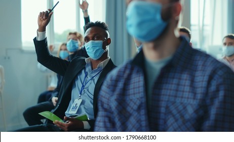 Diversity of corporate people in masks participating in conference meeting business seminar, raising hands to ask the speaker. Presentation. Social distance. Coronavirus. - Shutterstock ID 1790668100