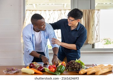 Diversity Gender Of LGBTQ Gay Couple Between Asian And African Ethnicity Cooking Together At Home Using Organic Vegetable To Make Salad And Sandwich