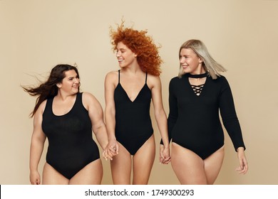 Diversity. Group Of Models With Different Body Types Portrait. Cheerful Blonde, Brunette And Redhead In Black Bodysuits Holding Hands. Female Friendship For Happy Life. 