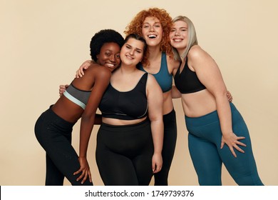 Diversity. Group Of Models Of Different Race, Figure And Size Portrait. Smiling Multicultural Women In Sportswear Against Beige Background. Body Positive As Lifestyle.