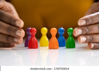 Diversity And Inclusion Concept. Hand Protecting Hand Colored Staff Pawns In Circle