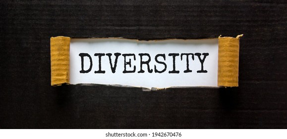 Diversity and inclusion symbol. The word 'Diversity' appearing behind torn black paper. Beautiful black background. Business, inclusion and diversity concept. Copy space.