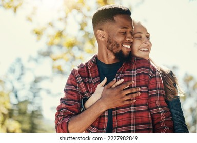 Diversity, love and couple hug in nature for relax summer holiday, outdoor freedom and happy quality time. African man, woman eyes closed and happiness together, hugging and loving in nature sunshine - Powered by Shutterstock