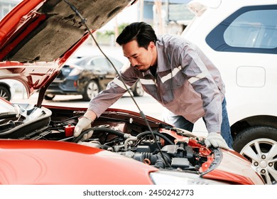 Diversity mechanic teamwork, a Japanese engineer wearing blue uniforms. A man inspects problems of the car engine inside opened car hood. Automobile repairing service. Vehicle maintenance. Labor work - Powered by Shutterstock