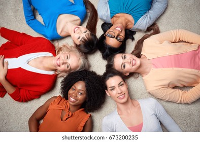 diversity, race, ethnicity and people concept - international group of happy smiling different women lying on floor in circle