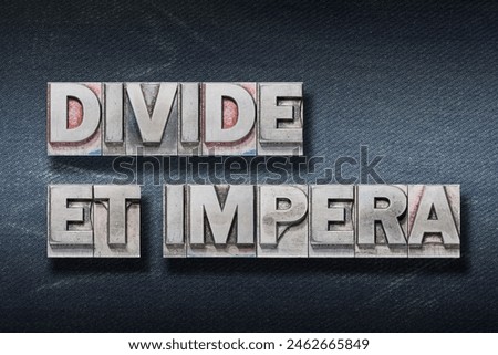 Divide et impera (Divide and conquer) phrase made from metallic letterpress on dark jeans background