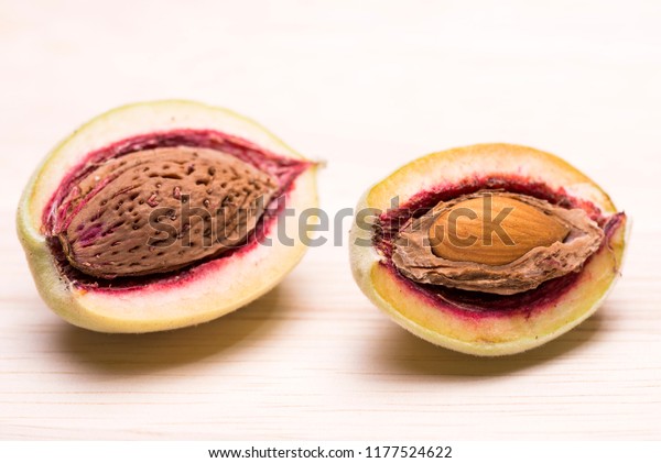Divided almond fruit in hard shell and kernel on a\
wooden table