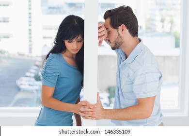 Divided couple are separated by white wall but holding hands