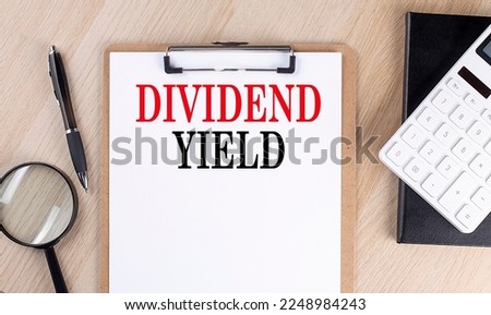 DIVIDEND YIELD text on clipboard on wooden background