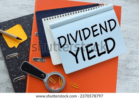DIVIDEND YIELD. text on notepad page on orange folder.