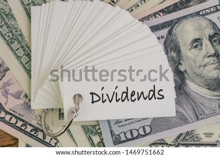 Dividends, return or earning that pay from stock or mutual fund investing concept, lot of paper notes with handwriting word Dividends on pile of US Dollar banknotes money.