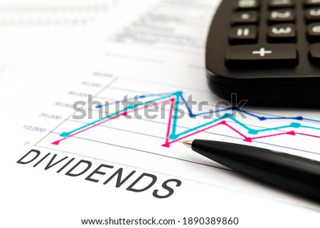 DIVIDENDS text on documents with graphs, charts, calculator, pen, financial concept background.