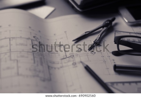 Divider, pencil, pen, ruler, glasses and smartphone\
and blueprint on table top.Table top view of Engineers table at\
office workplace.selective\
focus