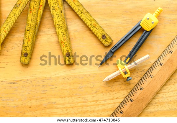 dividers and retro wooden ruler with\
folding metre ruler measuring on wooden table\
background