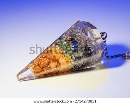 A divination pendulum with gemstone chips inside.