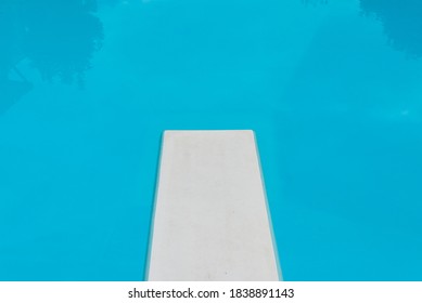 Diving Board And An Empty Swimming Pool, With Reflections In The Water