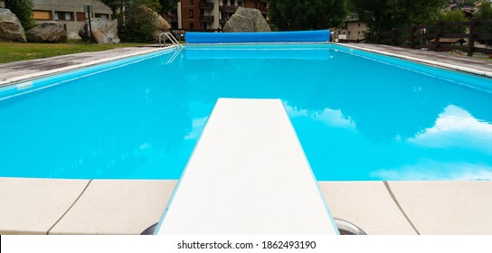 Diving board and an empty swimming pool, with reflections in the water