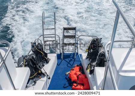 Diving equipment with oxygen tanks and fins sitting at the back of the tour boat.